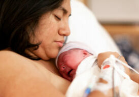 Mother holding her brand new baby girl in a hospital delivery room. Taken right after giving birth.