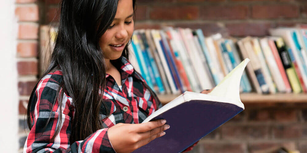 Young girl reading a book in a library