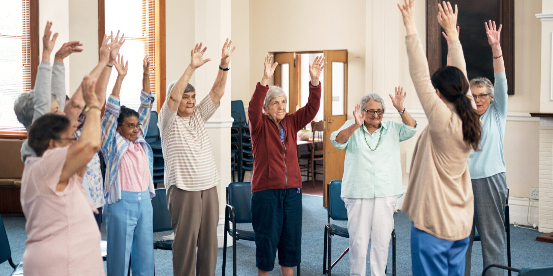 Full length shot of a female fitness instructor taking a class in an old age home