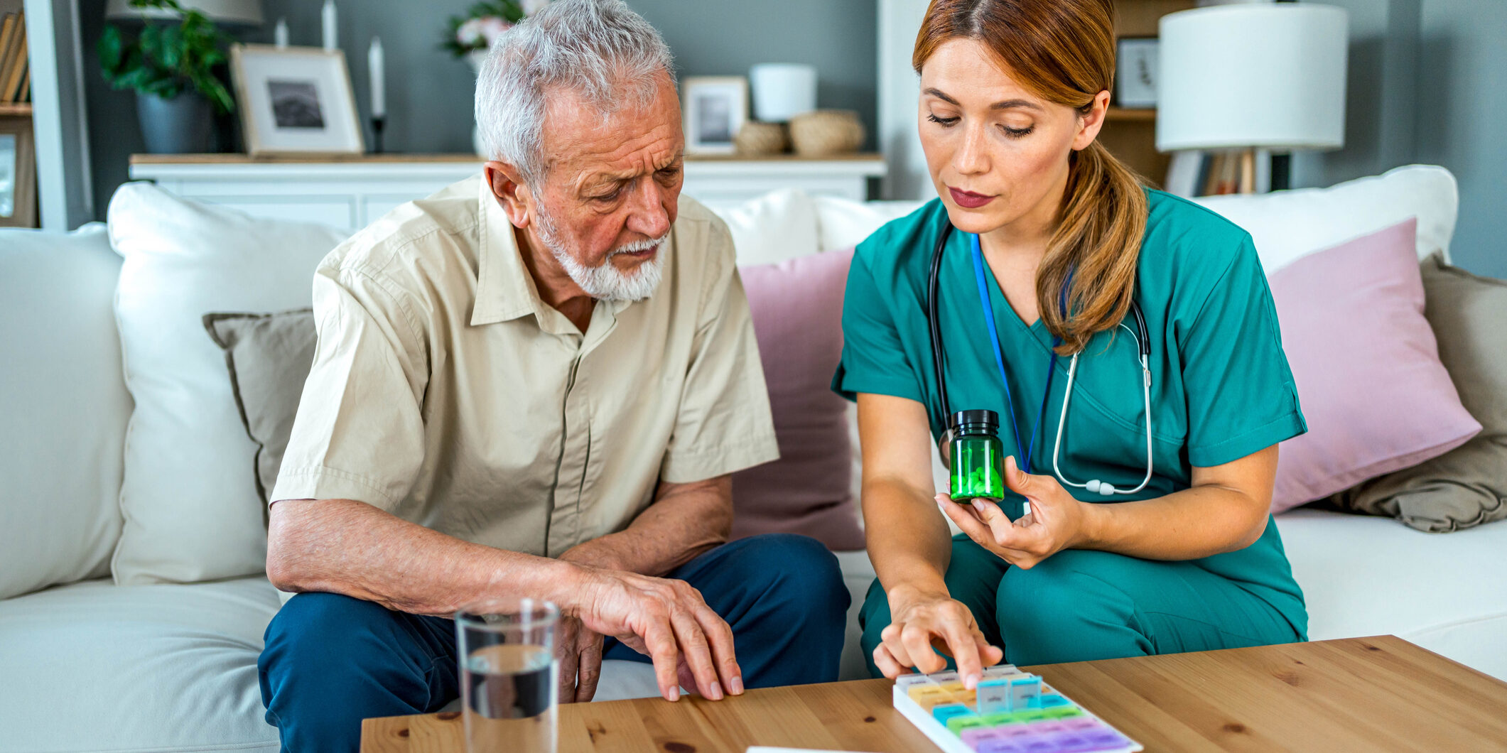 Female home nurse helping senior man to organize medication during a home visit