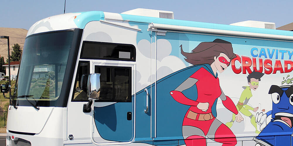 Mobile Health Unit with dental superhero graphics on the side